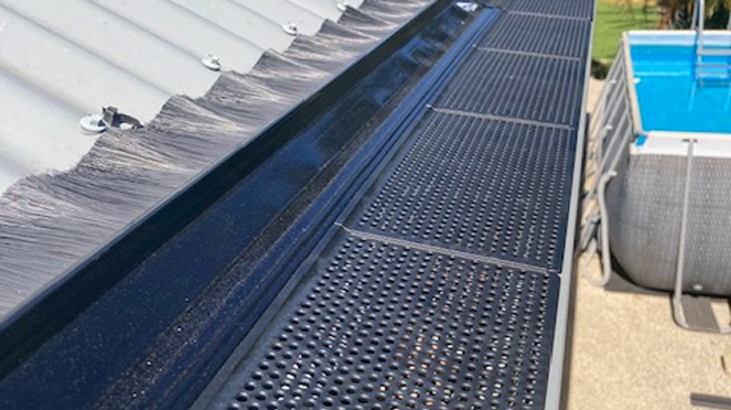 A metal roof vent topped with a black metal mesh gutter guard cover with holes for effective debris and pests protection made by Roof2Drain